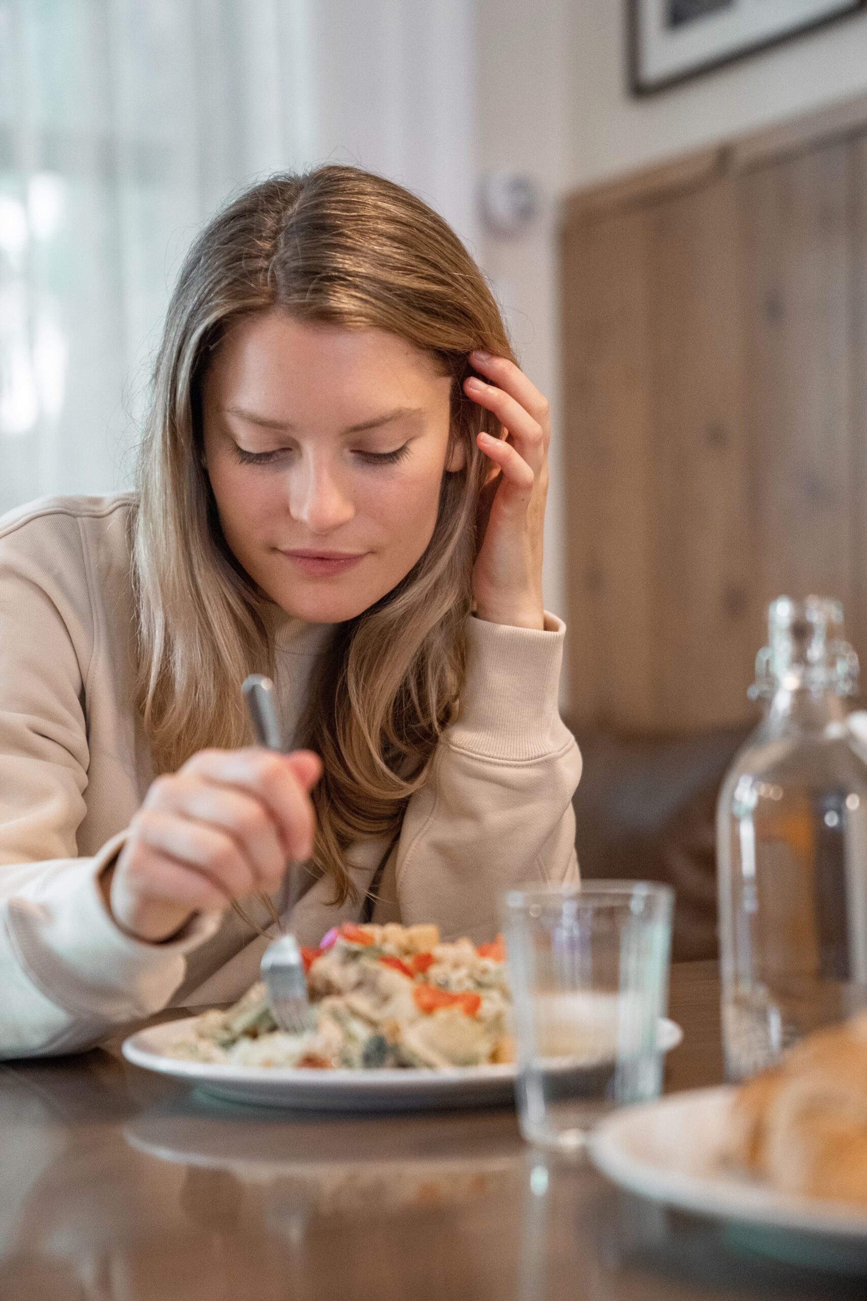 Femme souriante, paisible, regardant son assiette avec curiosité
